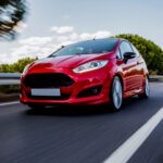 Red mini coupe driving highway with high speed